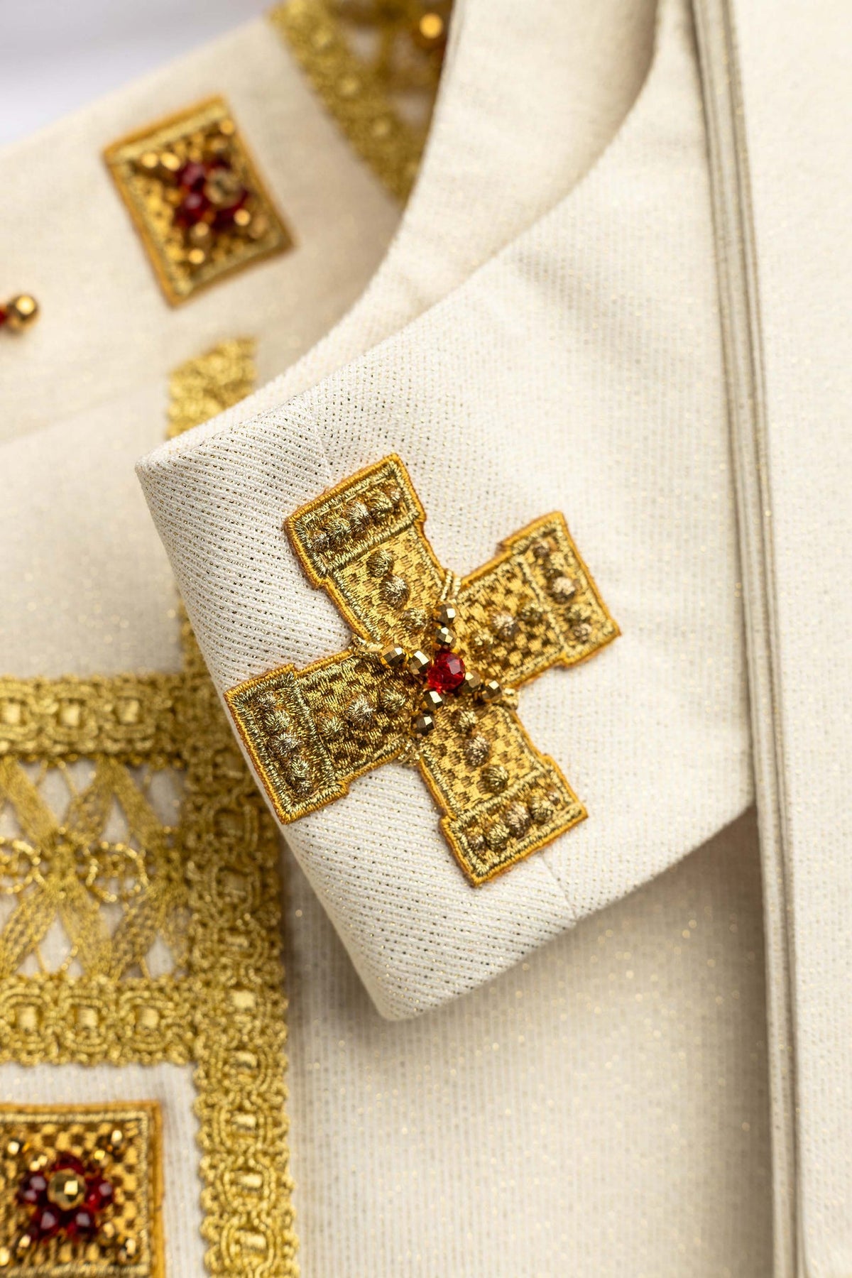 Handgefertigtes Messgewand mit Natursteinen, Detailaufnahme des goldenen Kreuzes mit roten Steinen