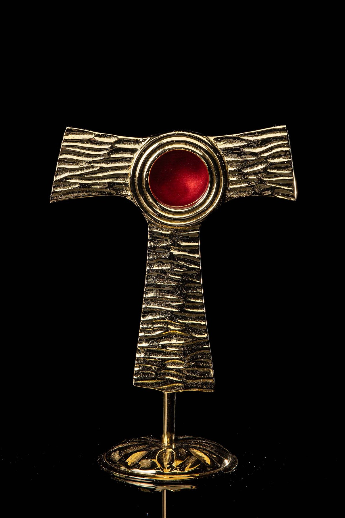 Reliquiar - Kreuz - Tau - Messing, vollständige Vorderansicht mit roter runder Reliquienfassung und Standfuß