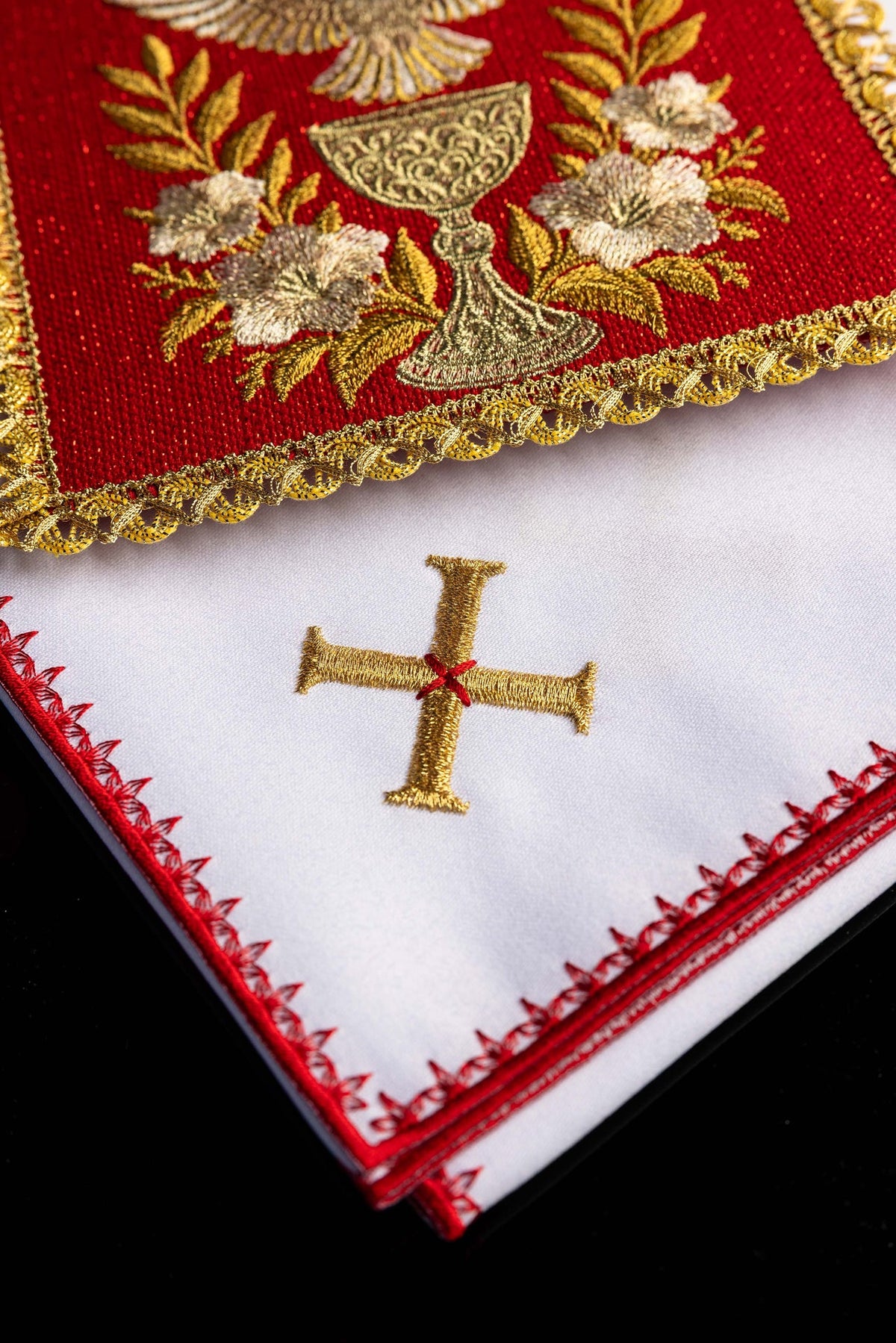 Kelchwäsche mit goldbesticktem Kreuz und roter Zierborte am weißen Tuch