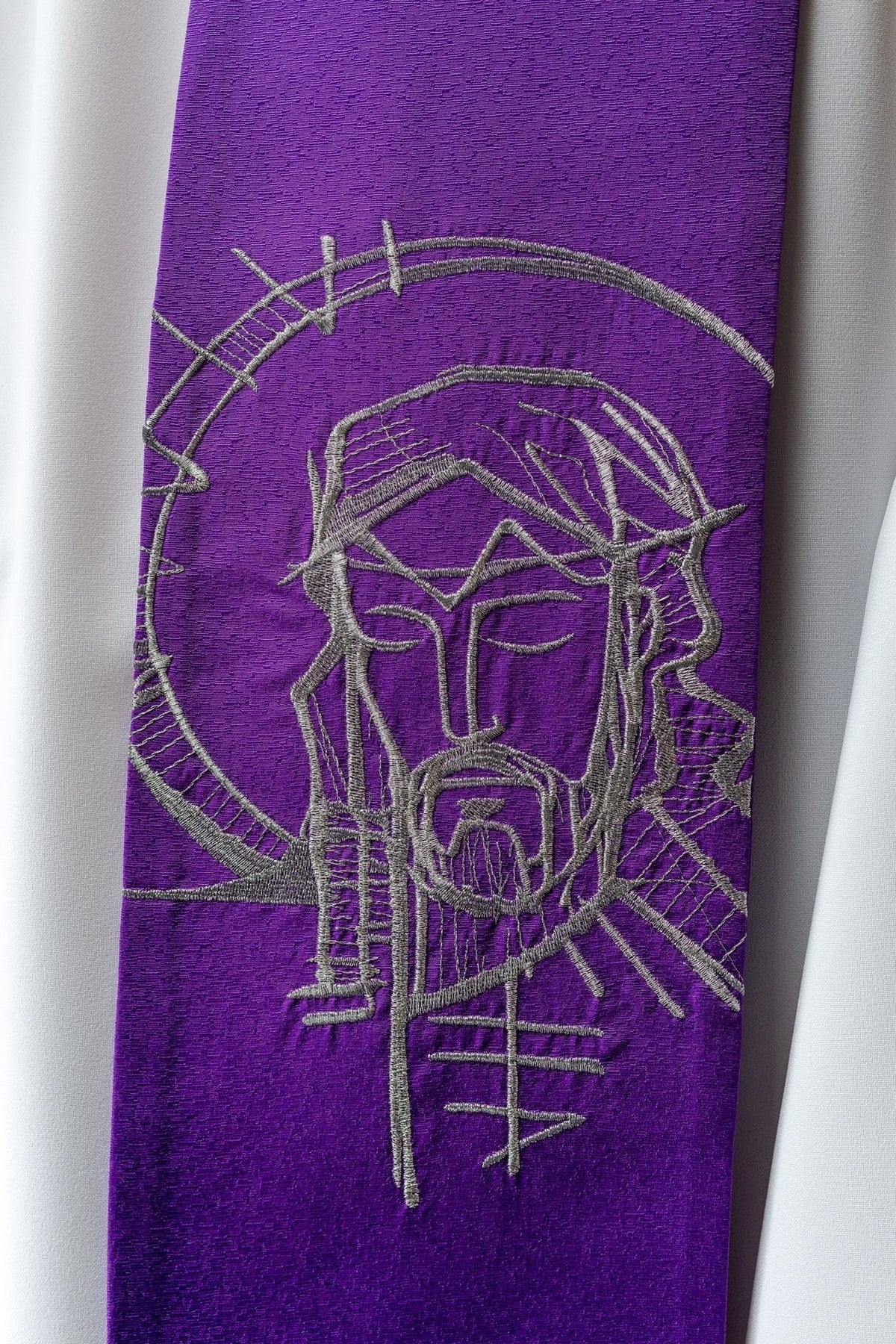 Stola mit Jesusmotiv, Nahaufnahme der silberfarbenen Stickerei auf violettem Stoff