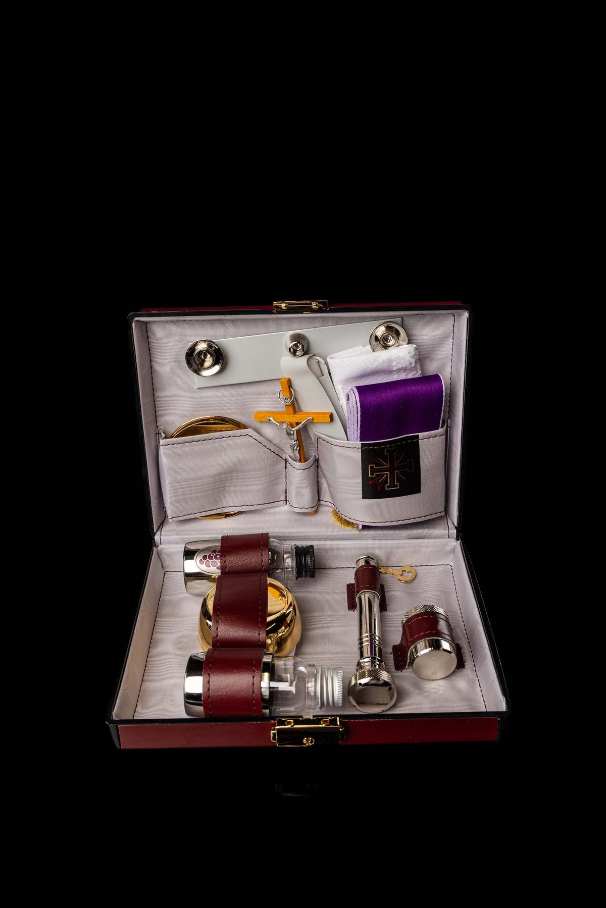 Geöffneter Missionskoffer mit Kelch, Kreuz, Weihrauchgefäßen, Fläschchen und violetten Tüchern