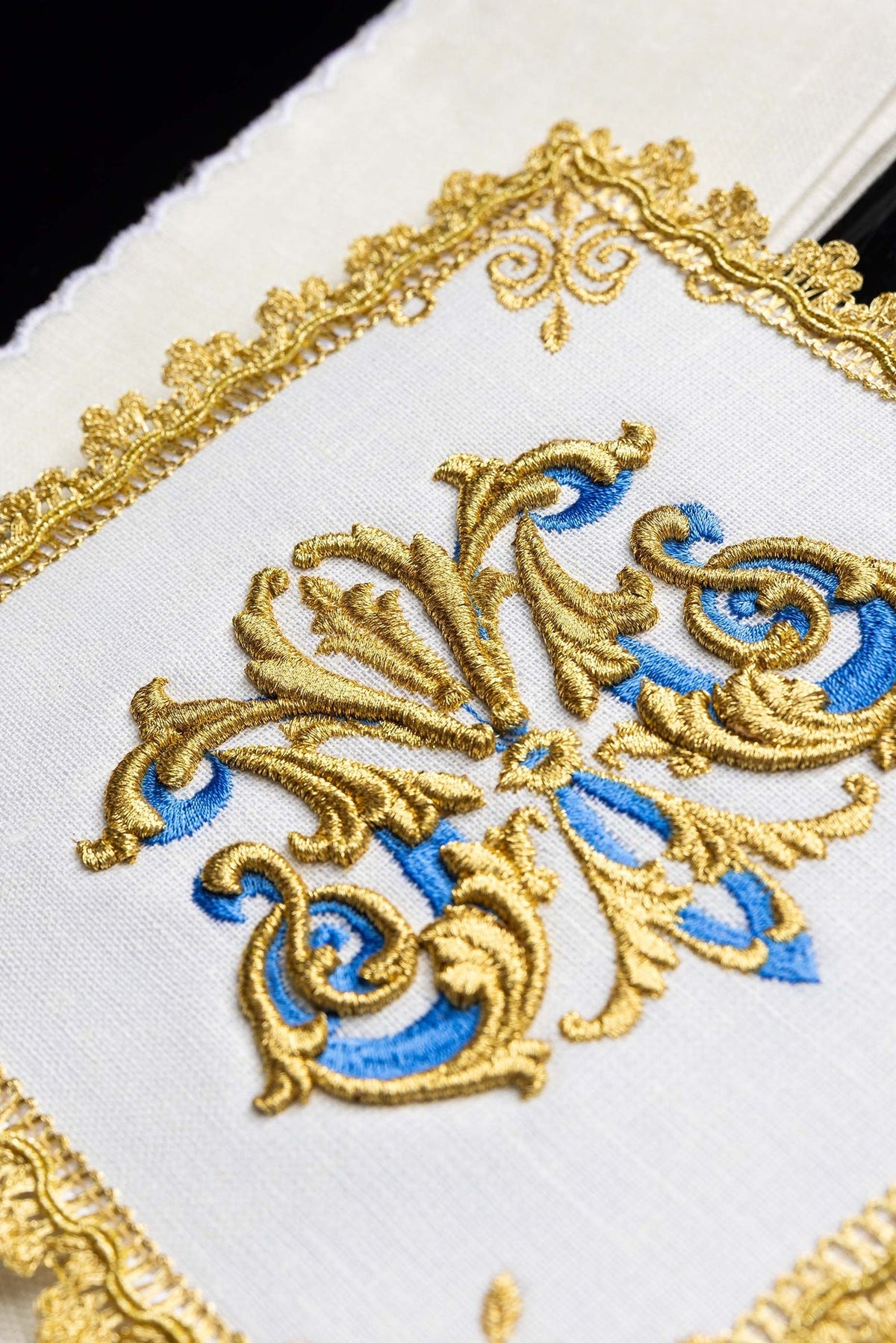 Kelchwäsche-Set mit Nahaufnahme der gold-blauen Stickerei auf Leinen