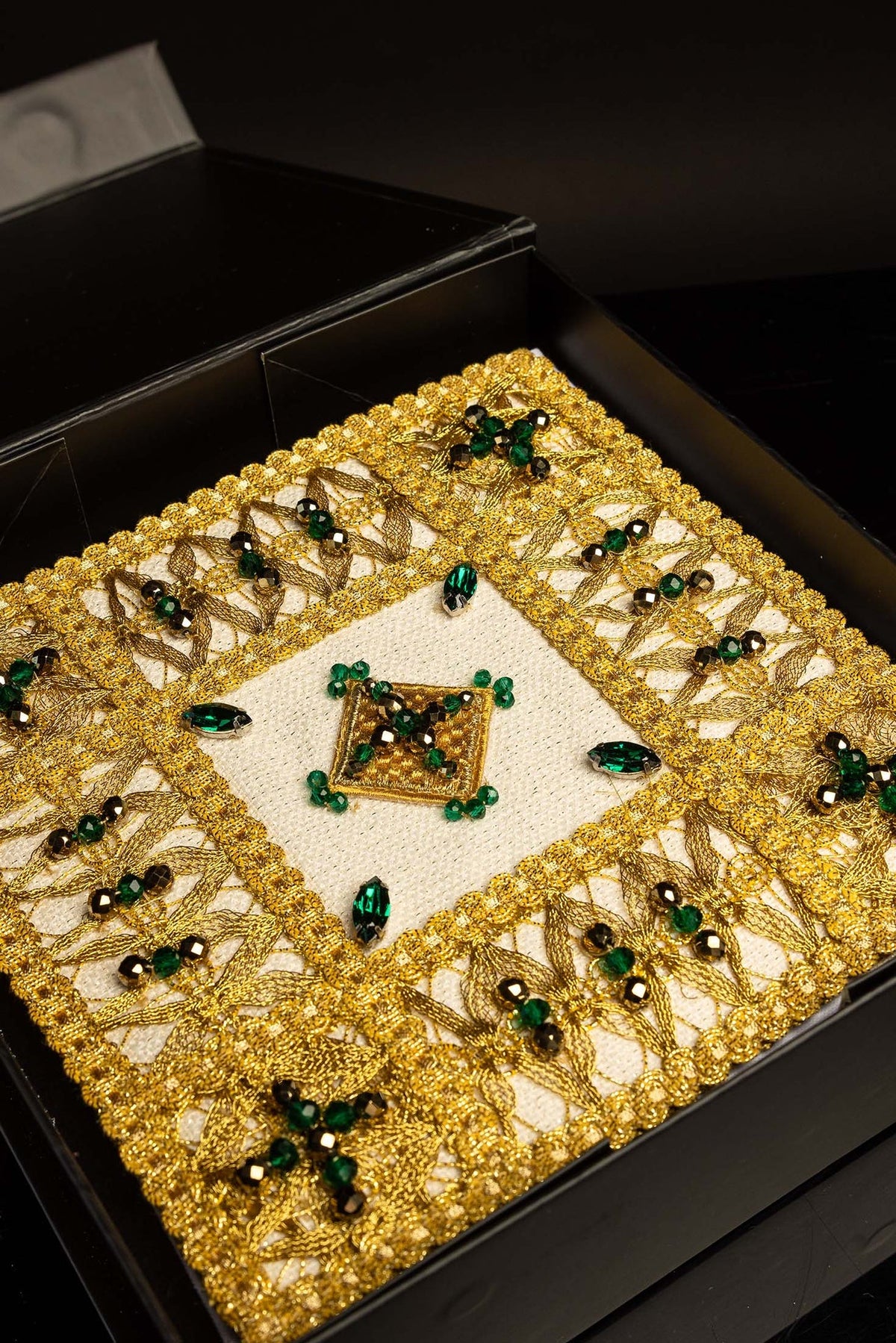 Kelchwäsche-Set im geöffneten schwarzen Etui mit goldener Verzierung und grünen Steinen
