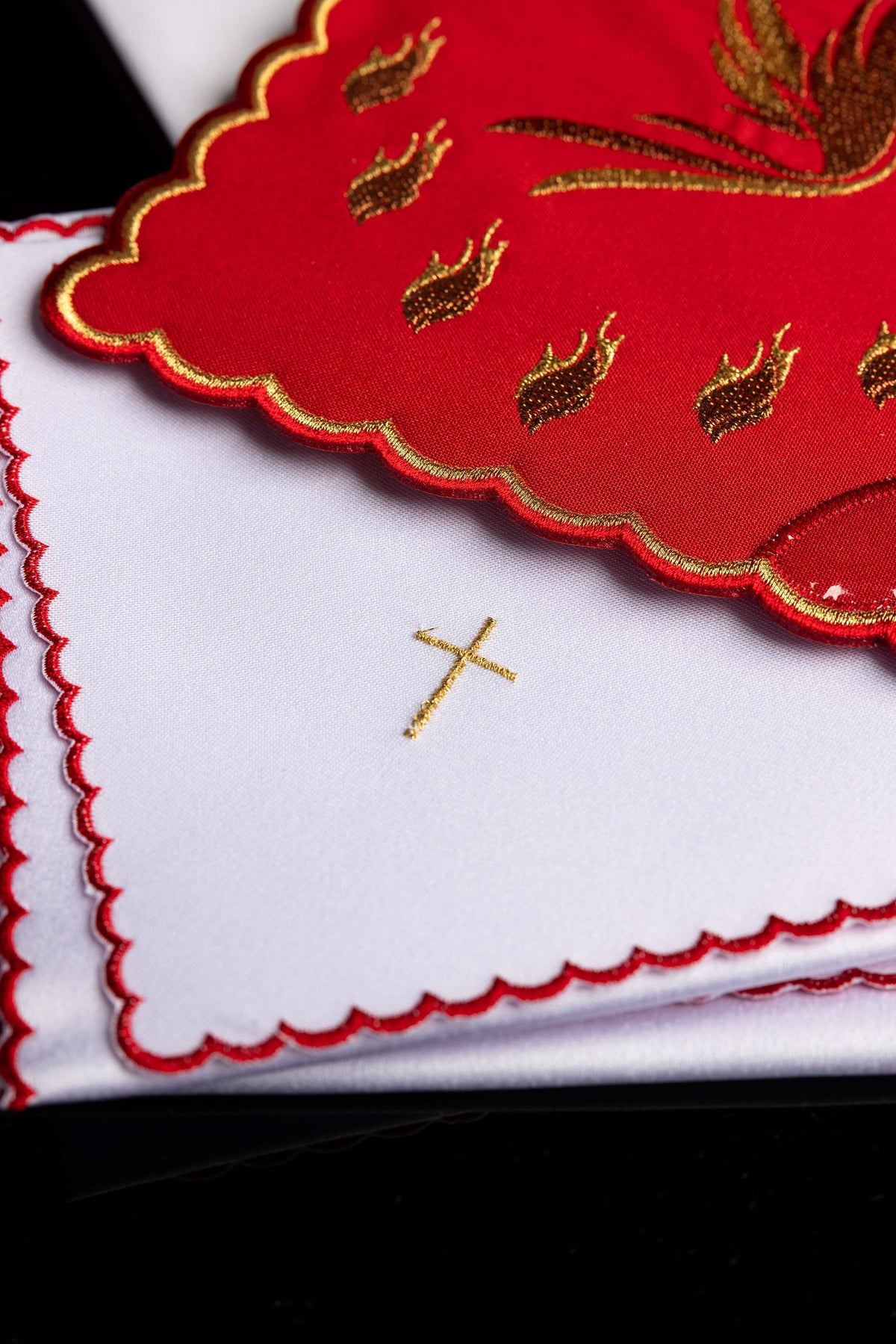 Kelchwäsche, Detail der roten Kante und des goldenen Kreuzes auf weißem Stoff