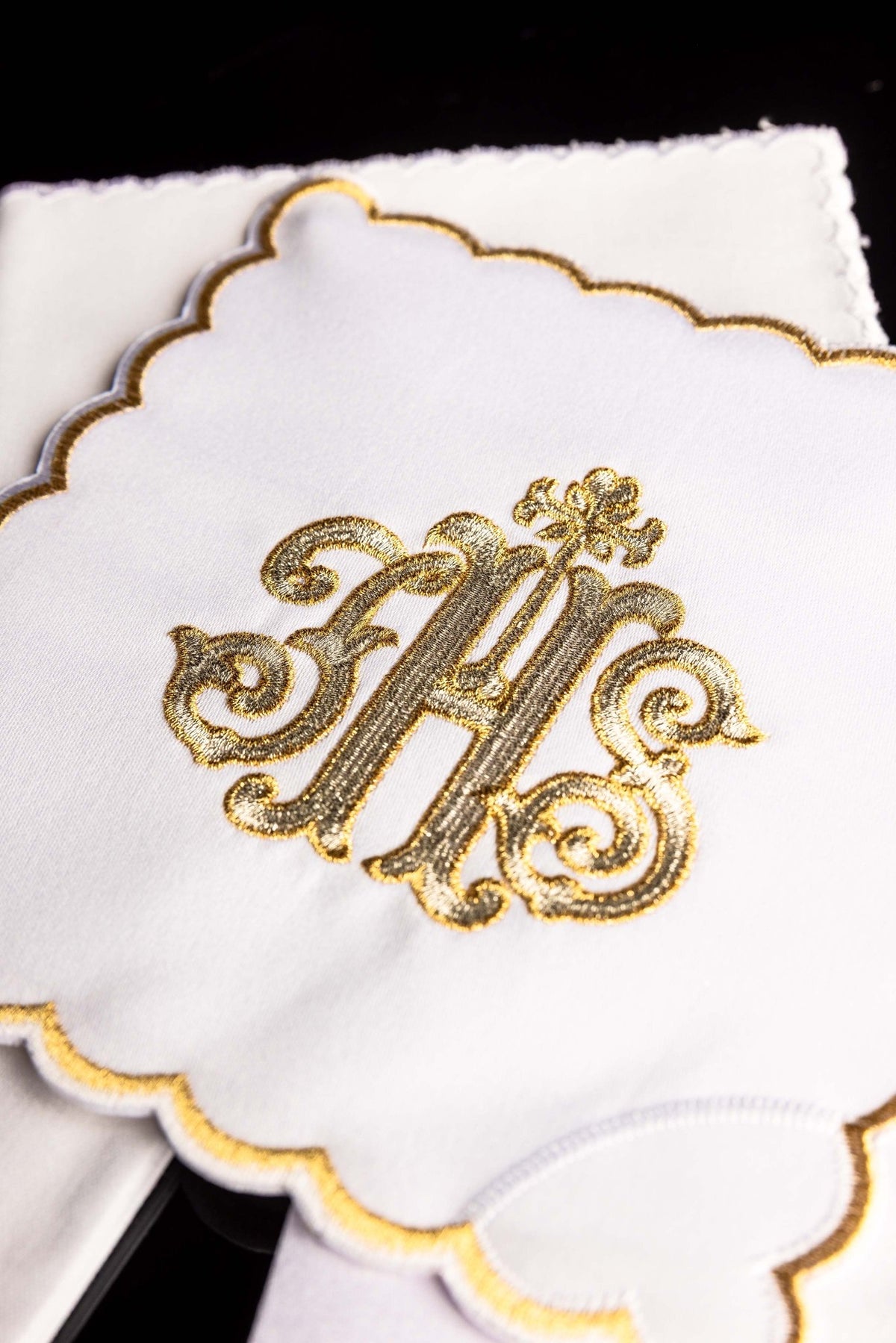 Kelchwäsche-Set mit goldener IHS-Stickerei, Detailansicht des weißen Tuchs mit Muschelkanten