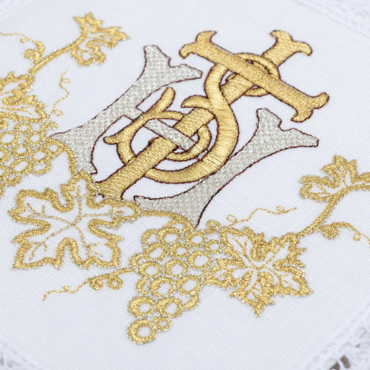 Kelchwäsche-Set mit Nahaufnahme der goldenen IHS- und Traubenstickerei auf weißem Stoff