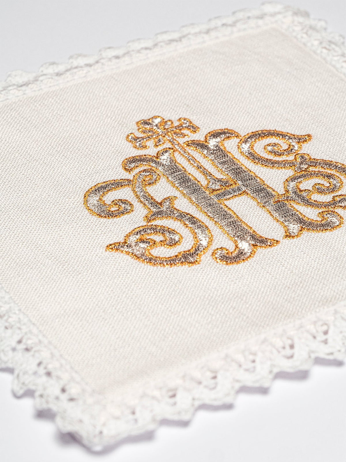 Kelchwäsche-Set, Nahaufnahme des goldenen IHS-Monogramms und Spitzenrands
