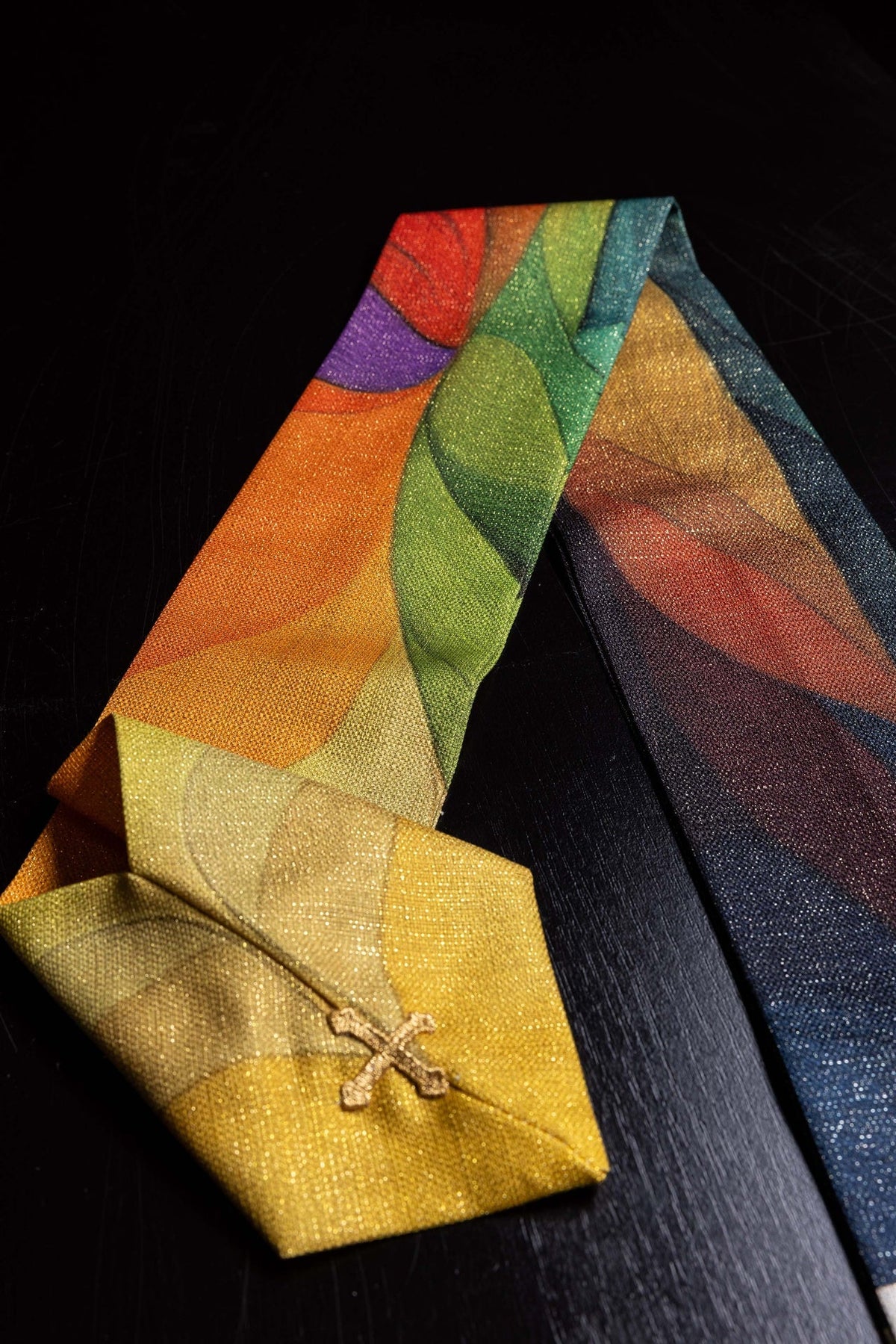 Mehrfarbig bedruckte Kasel mit Kreuzmotiv, Nahaufnahme des bunten Druckmusters und goldenen Kreuzdetails