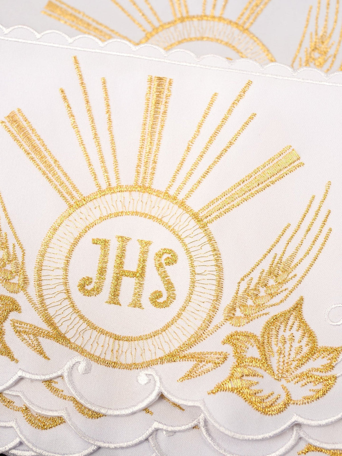 Weißes Meter mit goldener IHS-Stickerei, Detailansicht des Strahlenkranzes und floraler Ornamente