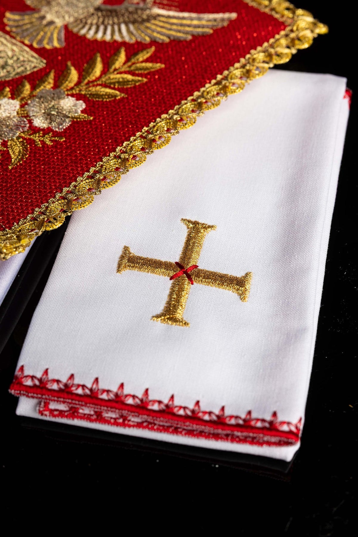Kelchwäsche mit weißem Tuch, goldbesticktem Kreuz und roter Randverzierung