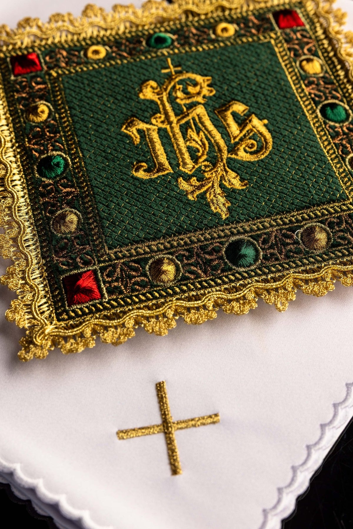 Kelchwäsche-Set mit Nahaufnahme des goldenen IHS-Monogramms auf grünem Einsatz